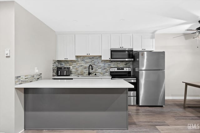 kitchen with white cabinets, a sink, ceiling fan, appliances with stainless steel finishes, and dark wood-style floors
