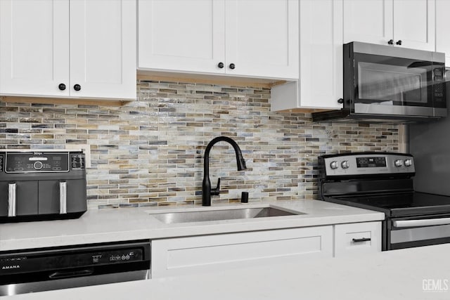 kitchen with a sink, light countertops, appliances with stainless steel finishes, and white cabinetry