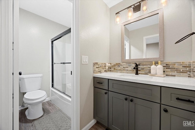 bathroom with toilet, wood finished floors, vanity, and backsplash