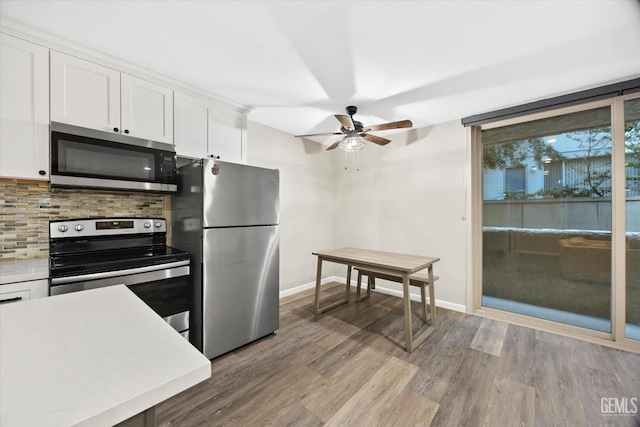 kitchen with ceiling fan, white cabinets, wood finished floors, stainless steel appliances, and backsplash
