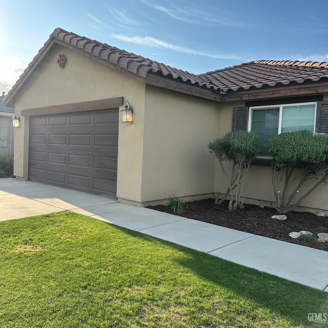 view of property exterior with a lawn, stucco siding, a tiled roof, an attached garage, and driveway