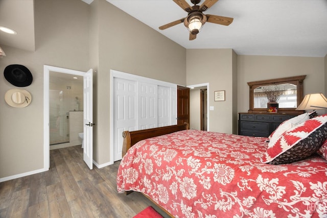 bedroom with a closet, dark wood-type flooring, vaulted ceiling, ensuite bath, and baseboards