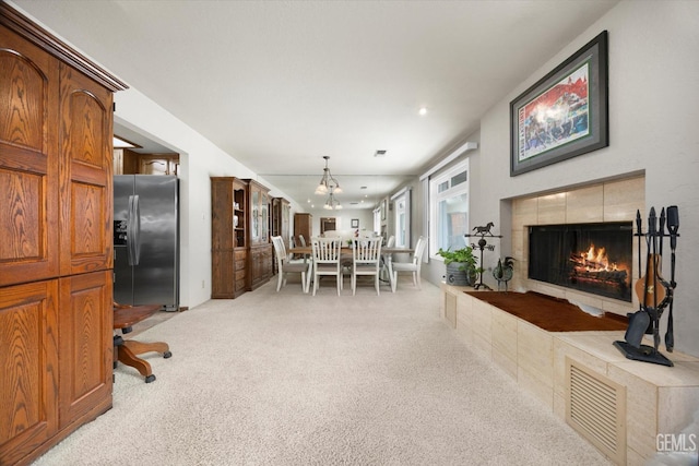 dining space featuring light carpet, recessed lighting, a chandelier, and a tile fireplace