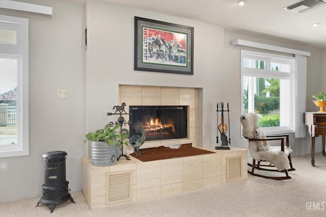 living area with carpet floors, a tile fireplace, and visible vents