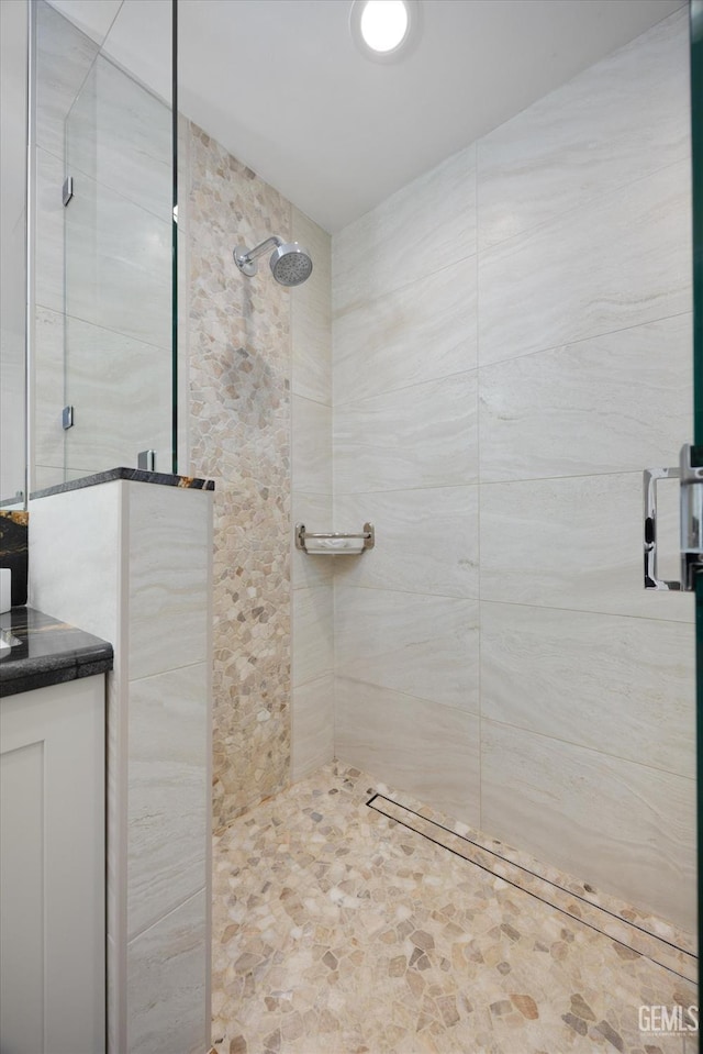 full bath featuring tiled shower and vanity