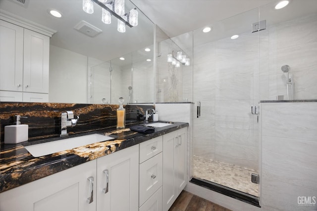 full bath with double vanity, wood finished floors, a stall shower, and a sink