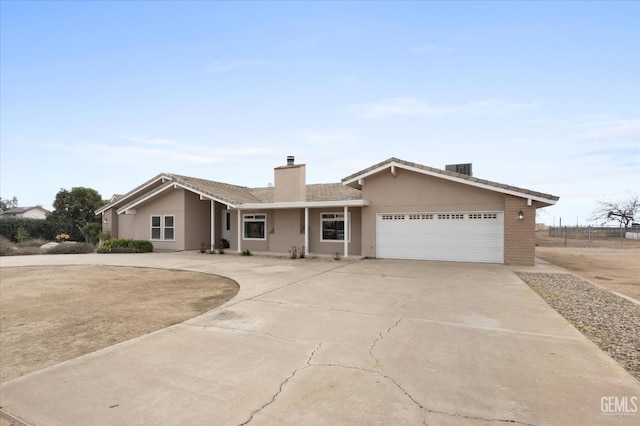 single story home with a garage, driveway, a chimney, and stucco siding