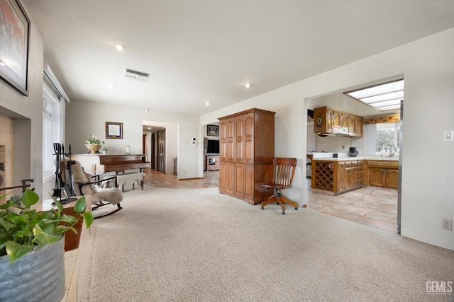 living room featuring light carpet, a fireplace, and visible vents