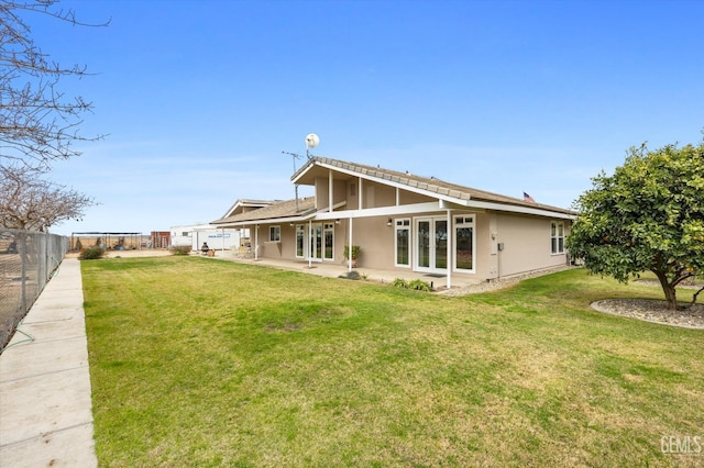 back of house with a fenced backyard, french doors, a lawn, stucco siding, and a patio area