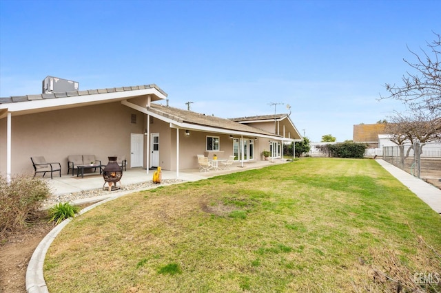 back of property with a yard, a patio area, fence, and stucco siding