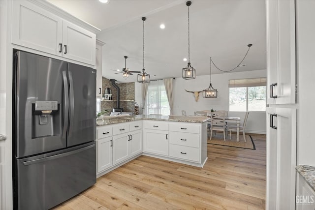 kitchen featuring a healthy amount of sunlight, light wood finished floors, stainless steel fridge, and white cabinets