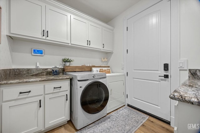 washroom with light wood-type flooring, cabinet space, and washer and dryer