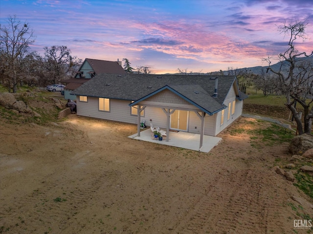 rear view of house with a shingled roof and a patio area