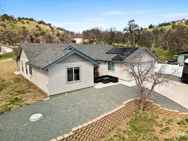 exterior space featuring roof mounted solar panels, a patio area, and roof with shingles