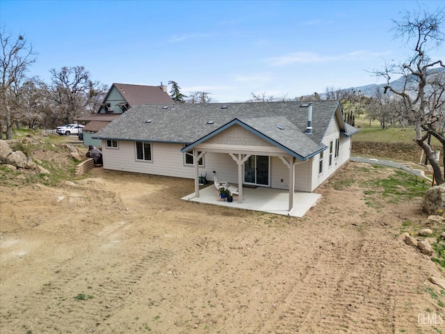 rear view of property featuring roof with shingles and a patio