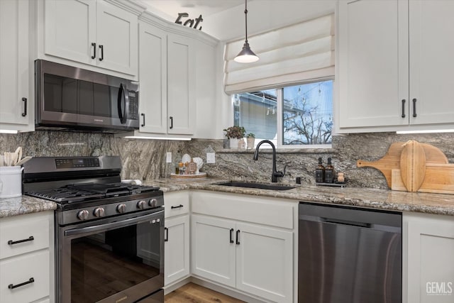 kitchen with stainless steel appliances, white cabinets, a sink, and backsplash