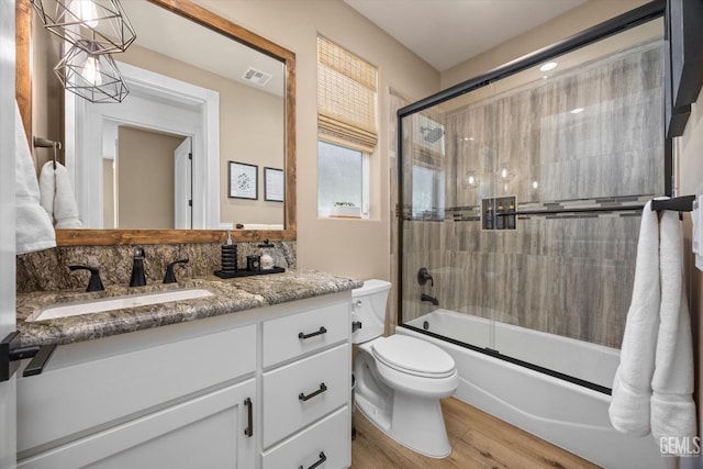 bathroom with enclosed tub / shower combo, toilet, wood finished floors, vanity, and visible vents