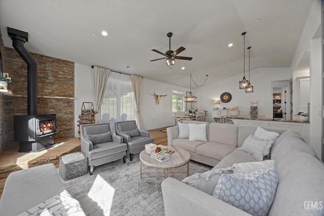 living room with recessed lighting, wood finished floors, a ceiling fan, vaulted ceiling, and a wood stove