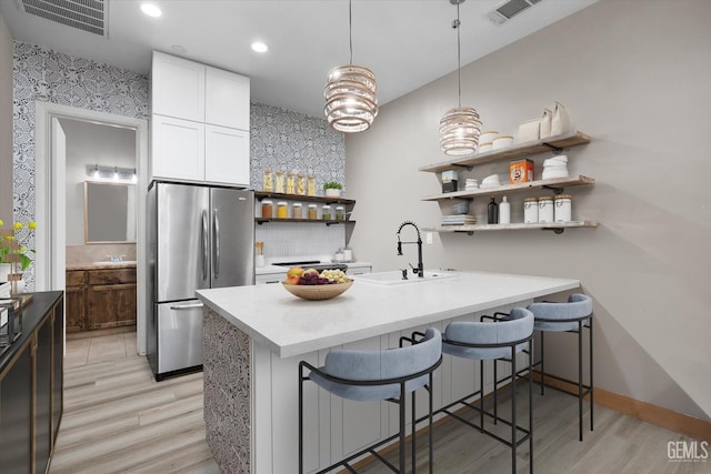 9200 Bridget Leigh Way, Bakersfield, CA 93312 - kitchen with freestanding refrigerator, open shelves, light wood-style floors, a kitchen breakfast bar, and tasteful backsplash