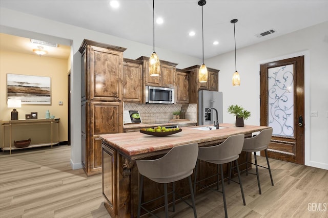 9200 Bridget Leigh Way, Bakersfield, CA 93312 - kitchen featuring appliances with stainless steel finishes, light wood-style floors, a center island with sink, decorative backsplash, and recessed lighting