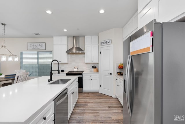 kitchen with white cabinetry, decorative light fixtures, stainless steel appliances, and wall chimney exhaust hood