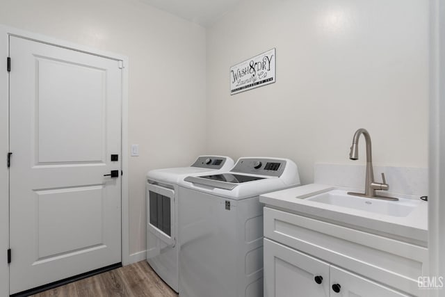 clothes washing area featuring sink, wood-type flooring, cabinets, and independent washer and dryer