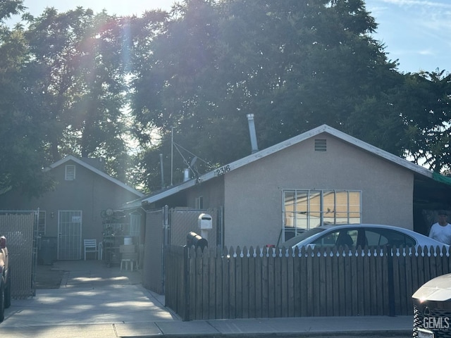 view of property exterior featuring a fenced front yard, stucco siding, and a gate