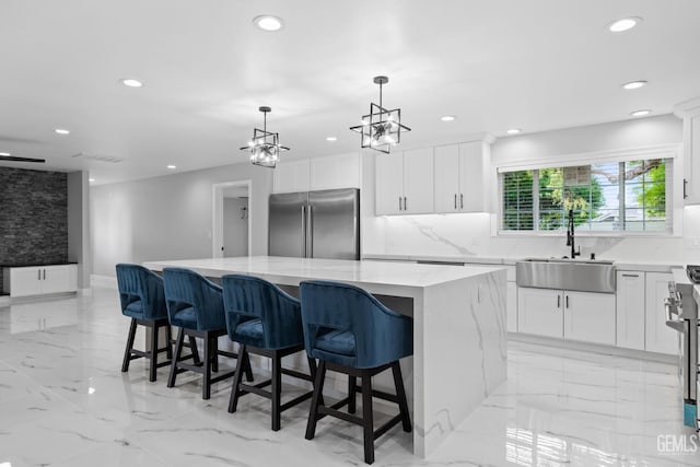 kitchen with high end appliances, a sink, recessed lighting, a kitchen island, and white cabinets