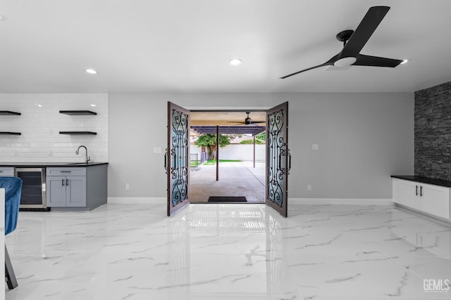 unfurnished living room featuring beverage cooler, ceiling fan, a sink, baseboards, and recessed lighting
