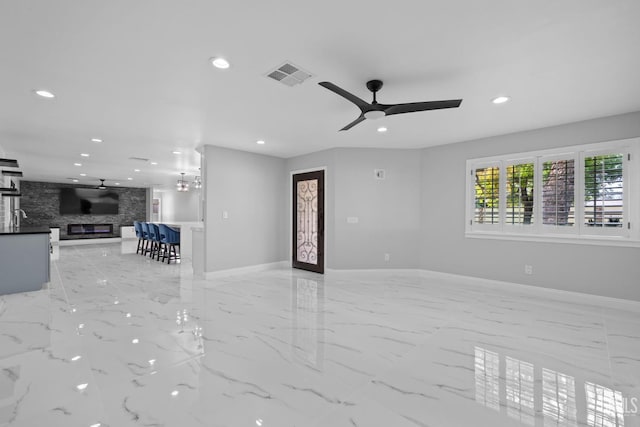 unfurnished living room featuring light marble finish flooring, recessed lighting, a ceiling fan, baseboards, and a large fireplace