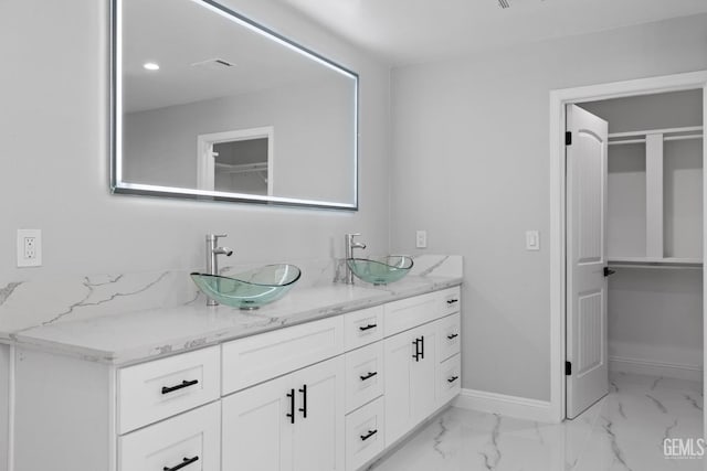 bathroom featuring double vanity, baseboards, and marble finish flooring