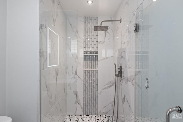 full bath with a marble finish shower and toilet