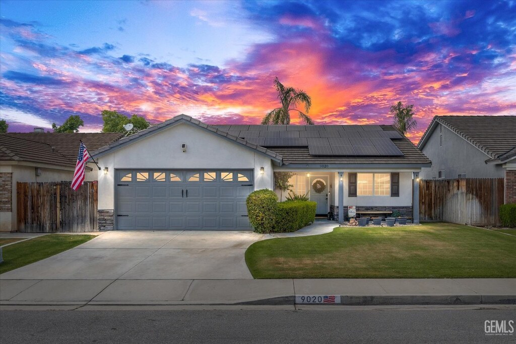 9020 Winlock St, Bakersfield, CA 93312 - ranch-style home with driveway, solar panels, fence, a front lawn, and an attached garage