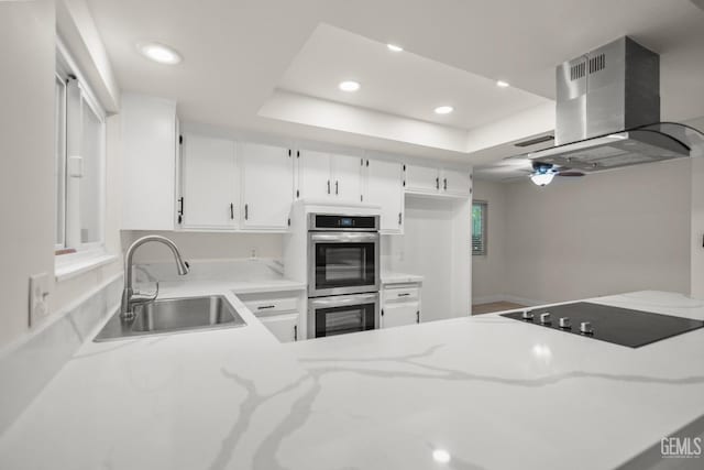 kitchen featuring light stone counters, a sink, island range hood, stainless steel double oven, and recessed lighting