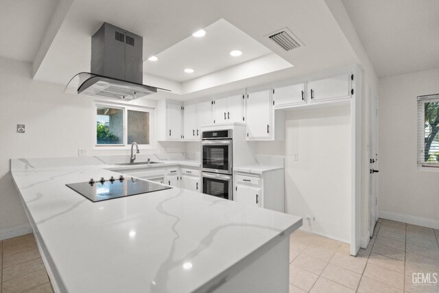 kitchen with black electric cooktop, stainless steel double oven, visible vents, island range hood, and a peninsula