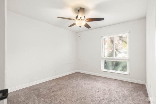 carpeted spare room featuring baseboards and ceiling fan
