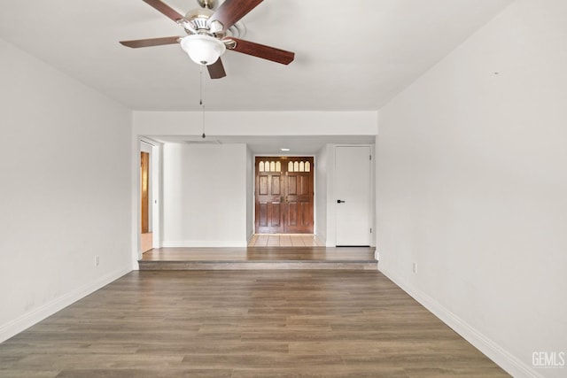 empty room featuring wood finished floors, baseboards, and ceiling fan