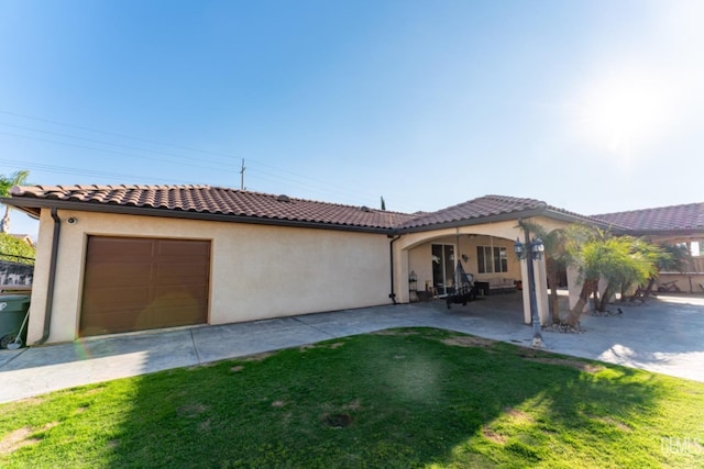 mediterranean / spanish-style house with driveway, a front yard, a tile roof, and stucco siding