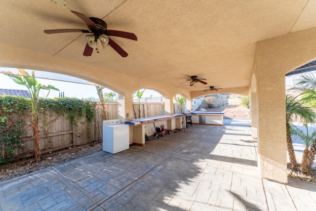 view of patio with a swimming pool, fence, and a ceiling fan