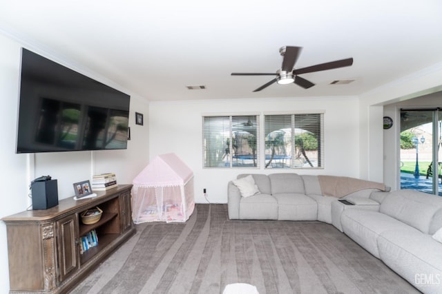 living room featuring ceiling fan, visible vents, and crown molding