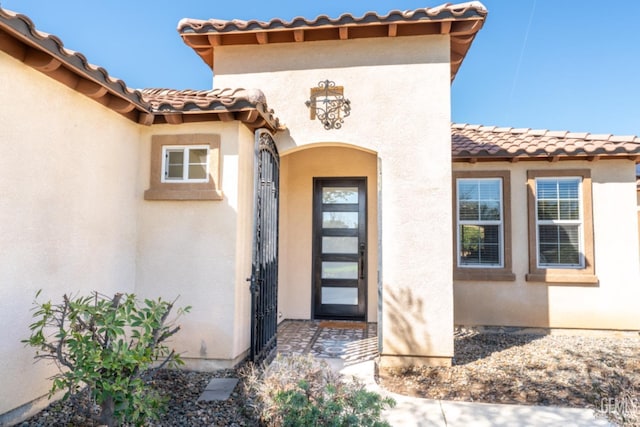 view of exterior entry featuring a tile roof and stucco siding