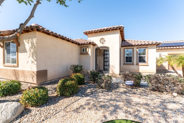 mediterranean / spanish house with roof mounted solar panels and stucco siding