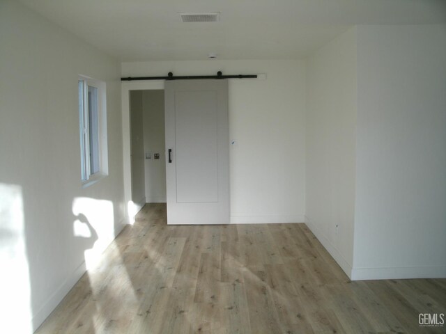 3111 Bucknell St, Bakersfield, CA 93305 - empty room with a barn door, light wood finished floors, and baseboards