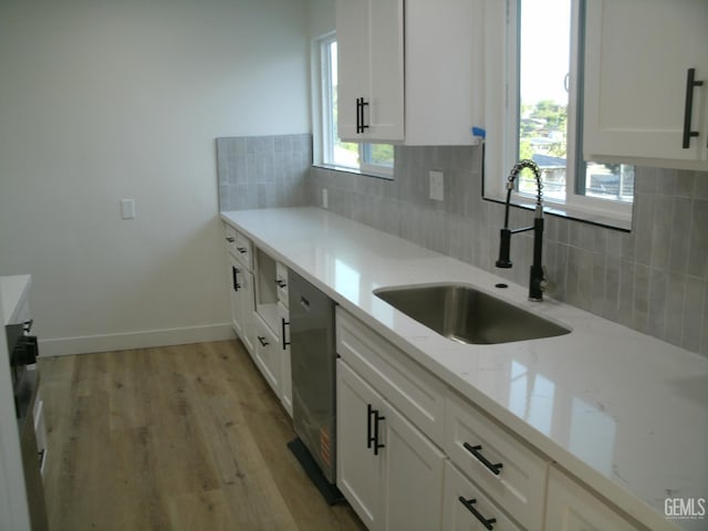 3111 Bucknell St, Bakersfield, CA 93305 - kitchen with a sink, white cabinetry, backsplash, light stone counters, and light wood-style flooring