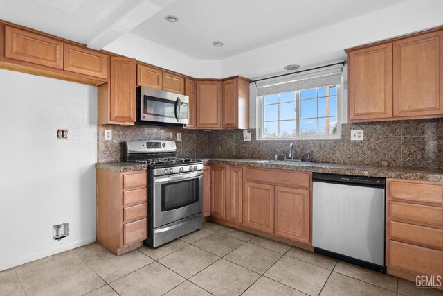 kitchen with decorative backsplash, sink, light tile patterned floors, and stainless steel appliances