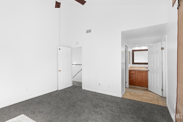 unfurnished bedroom featuring carpet, a high ceiling, ensuite bath, and ceiling fan