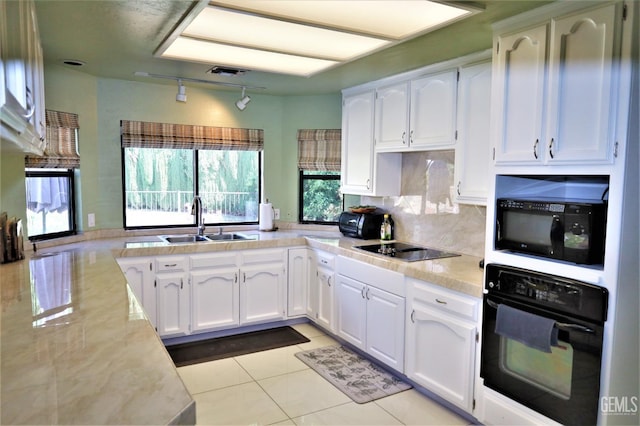 kitchen featuring sink, white cabinetry, light tile patterned floors, and black appliances