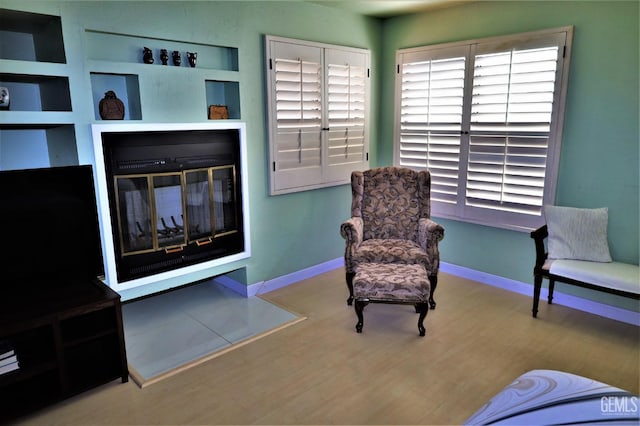 living area featuring built in shelves and light hardwood / wood-style floors