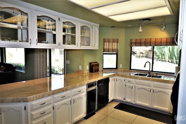 kitchen with light tile patterned floors, black dishwasher, white cabinets, and sink