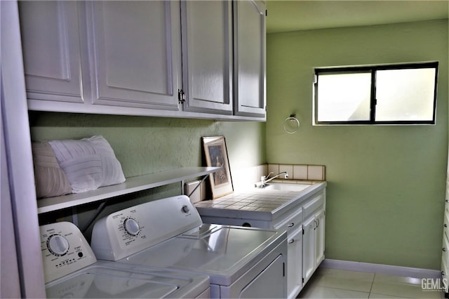 laundry room with light tile patterned floors, sink, washer and dryer, and cabinets